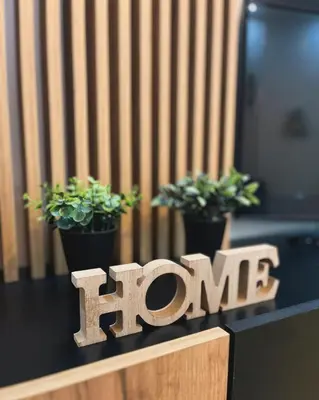 a wooden sign that says home next to potted plants at Apartman Sunshine in Doboj