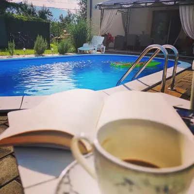 a cup of coffee and a book next to a swimming pool at Riverside Plaza in Bihać