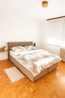 a white bed in a bedroom with a wooden floor at Apartman Centar Banja Luka in Banja Luka