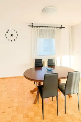 a dining room table with chairs and a clock on the wall at Apartman Centar Banja Luka in Banja Luka