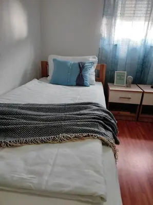 a bed with a blue pillow and a blanket on it at Apartman 