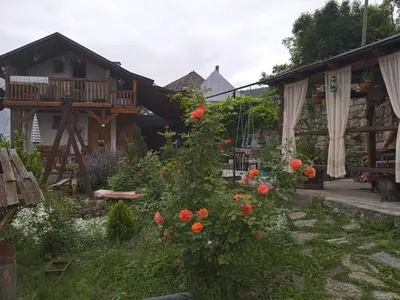 a garden with orange flowers in front of a house at Privatni smještaj Kurtalija in Jajce