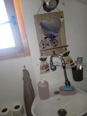a bathroom with a sink with a heart picture on the wall at Privatni smještaj Kurtalija in Jajce