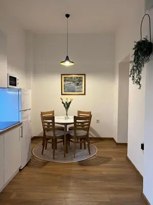 a dining room with a table and chairs and a kitchen at Penthouse City Center in Bihać