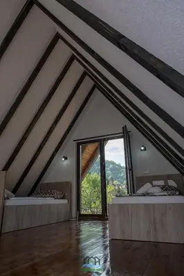 a attic room with two beds and a large window at Holiday Houses Green Queen in Bihać