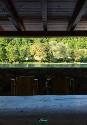 a table with chairs and a view of a lake at Holiday Houses Green Queen in Bihać