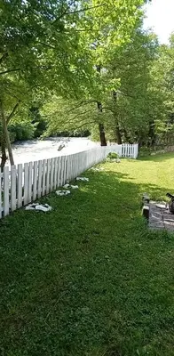 a white fence in the grass next to a river at Apartman Amina-Ahmad Vinac-Jajce in Jajce