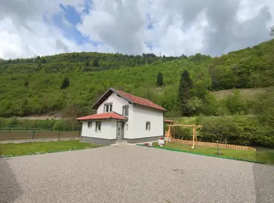 a white house with a hill in the background at Apartman Amina-Ahmad Vinac-Jajce in Jajce