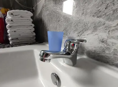 a bathroom sink with a faucet with a cup on it at Apartman Amina-Ahmad Vinac-Jajce in Jajce