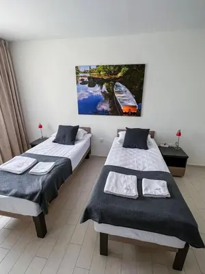 a bedroom with two beds and a painting on the wall at Happy Hill Rooms in Banja Luka