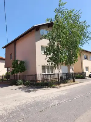 a building with a tree next to a fence at Studio Apartman 11 in Bihać