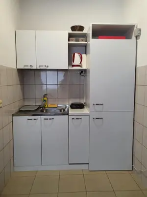 a kitchen with white cabinets and a white refrigerator at Studio Apartman 11 in Bihać