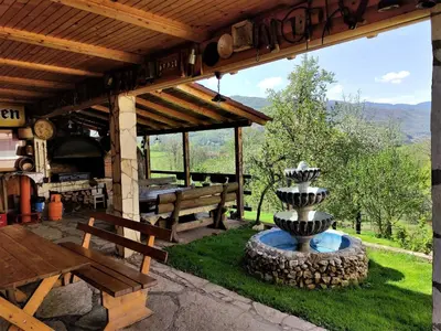 a patio with a stone fountain and a picnic table at Apatments Radoja - Pliva in Šipovo
