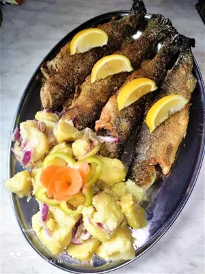 a plate of food with fish with lemon slices on it at Apatments Radoja - Pliva in Šipovo