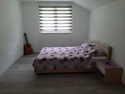 a bedroom with a bed and a window with a guitar at Apartman Dujmović in Visoko