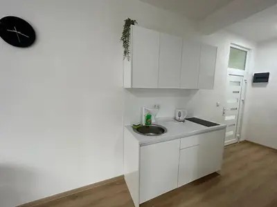 a white kitchen with a sink and a clock on the wall at Apartmani Art in Jajce