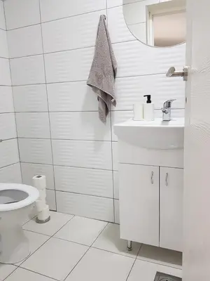 a white bathroom with a toilet and a sink at Apartmani Art in Jajce