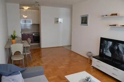 a living room with a television and a table with chairs at Apartment Lazarus Banja Luka in Banja Luka