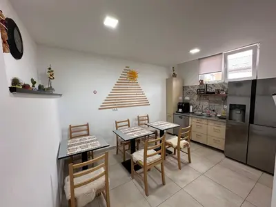 a kitchen with two tables and chairs and a refrigerator at Ravne Energy Apartments in Visoko
