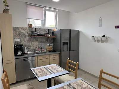 a kitchen with a table and a stainless steel refrigerator at Ravne Energy Apartments in Visoko