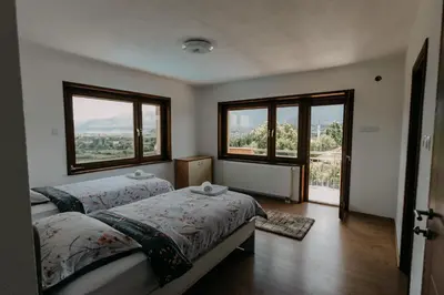 a bedroom with two beds and two large windows at Villa Lamija in Bihać