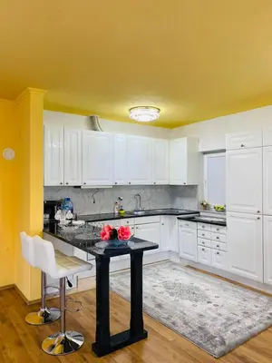 a kitchen with a black table and white cabinets at Apartman Kula in Gradačac
