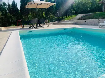 a swimming pool with a table and an umbrella at Vikendica Nature park Banja Luka in Banja Luka