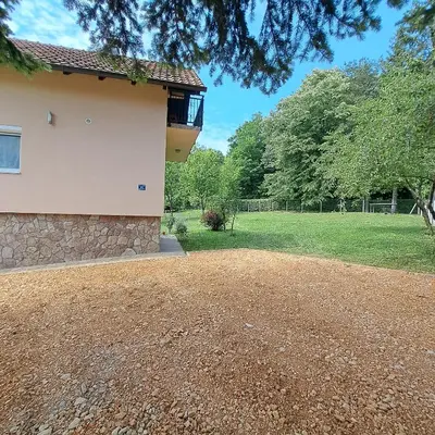 a house with a gravel driveway in front of a yard at Vikendica Nature park Banja Luka in Banja Luka