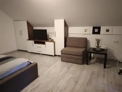 a bedroom with a bed and a chair and a television at Vikendica Nature park Banja Luka in Banja Luka
