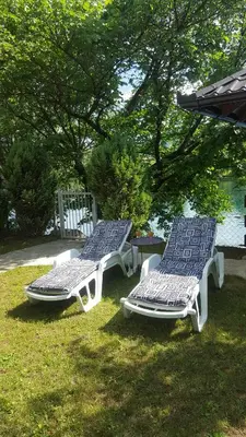 two lounge chairs sitting in the grass under a tree at Lahor in Bihać