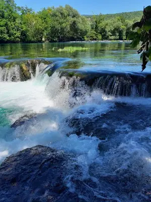 a river with waterfalls and trees in the background at Lahor in Bihać