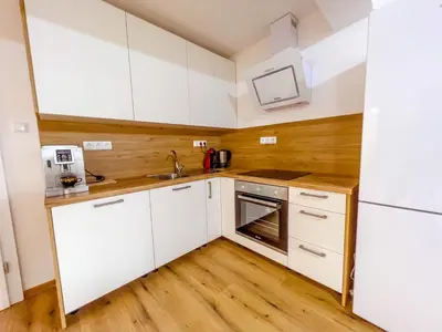 a kitchen with white cabinets and a wooden floor at Daman Villa in Bihać