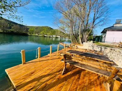 a wooden dock with two benches on the water at Daman Villa in Bihać
