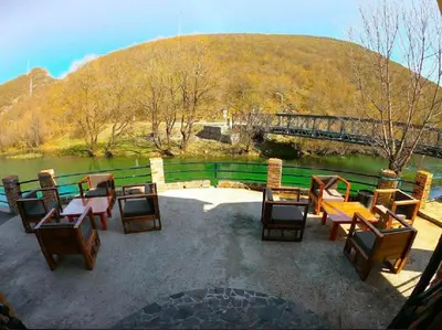 a group of tables and chairs next to a body of water at Vila Sana in Landeke