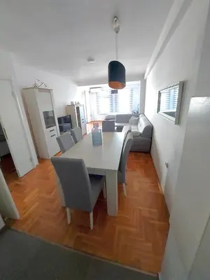 a dining room and living room with a table and chairs at Apartman CITY CENTER 4-šetalište in Prijedor