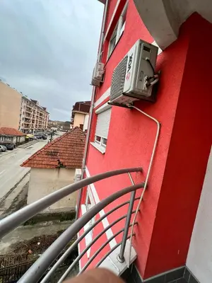 a balcony of a red building with a air conditioner at Apartman Lana in Doboj