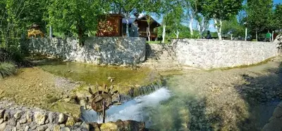 a pool of water in a yard with a stone wall at Rest House Ripac in Praščijak