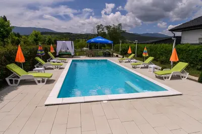 a swimming pool with lounge chairs and umbrellas at Holiday Home Bonum in Bihać