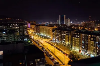 a city at night with cars parked in a parking lot at A First class za 4 osobe 2 spavaće sobe in Tuzla