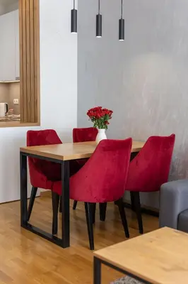 a dining room table with red chairs and a vase with flowers at Drobac apartman in Banja Luka