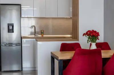 a kitchen with a table and red chairs and a sink at Drobac apartman in Banja Luka