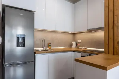 a kitchen with white cabinets and a stainless steel refrigerator at Drobac apartman in Banja Luka