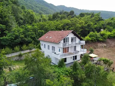 a white house in the middle of a forest at Amani in Kovačevo Polje