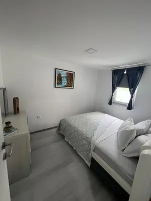 a white bedroom with a bed and a window at Amani in Kovačevo Polje