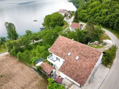 an aerial view of a house on the shore of a lake at Amani in Kovačevo Polje