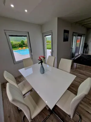 a white dining room table with white chairs and a vase with flowers at Villa Eda in Bihać