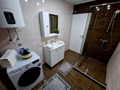 a bathroom with a shower and a sink and a washing machine at Villa Eda in Bihać