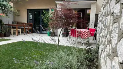 a yard with chairs and a table and a stone wall at Visoko New Concept - 7 minutes from the Pyramids - City Center in Visoko