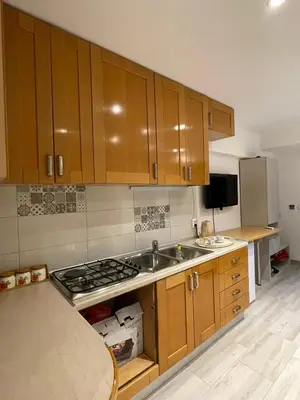 a kitchen with wooden cabinets and a sink and a stove at Visoko New Concept - 7 minutes from the Pyramids - City Center in Visoko