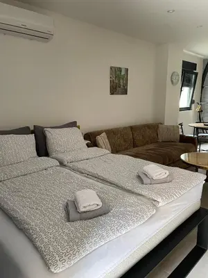 a large bed in a living room with two pillows on it at Visoko New Concept - 7 minutes from the Pyramids - City Center in Visoko